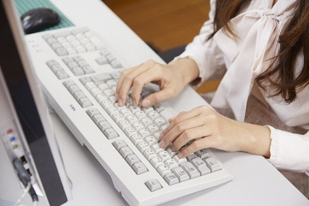 真っ白のキーボードを打つ女性の手